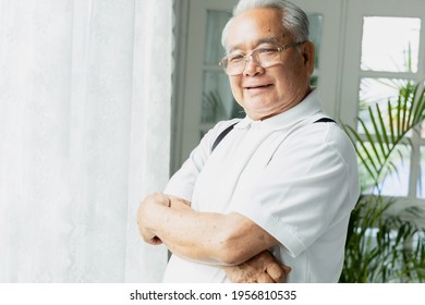 Portrait Of An Asian Old Man Smiling And Holding His Chest By The Window.