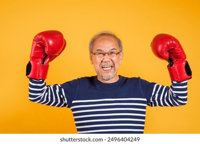 Portrait Asian old man wearing glasses wear two red boxing gloves studio shot isolated yellow background, smiling happy elderly man gray haired healthy fighter lifestyle concept - Powered by Shutterstock