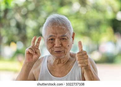 A Portrait Of Asian Old Retire Who Has Alzheimer's Disease. Laughing 80 Year Old Senior Man Candid Portrait Very Happy When Go To Park. Funny Senior Asian Man Looking At Camera. Concept Happy People .
