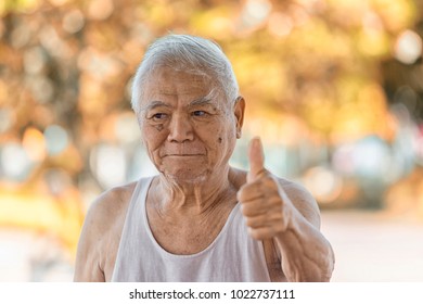 A Portrait Of Asian Old Retire Who Has Alzheimer's Disease.Laughing 80 Year Old Senior Man Candid Portrait Very Happy When Go To Park. Funny Senior Asian Man Looking At Camera. Concept Happy People.