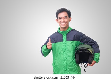 Portrait Of Asian Online Taxi Driver Wearing Green Jacket Showing Thumb Up Hand Gesture And Holding Helmet. Isolated Image On White Background