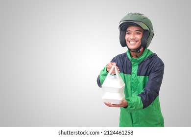 Portrait Of Asian Online Taxi Driver Wearing Green Jacket And Helmet Holding Food Wrapped In Foam Plastic Box. Isolated Image On White Background