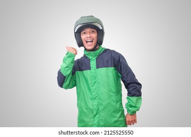 Portrait Of Asian Online Taxi Driver Wearing Green Jacket And Helmet Pointing At Empty Space With Finger. Isolated Image On White Background