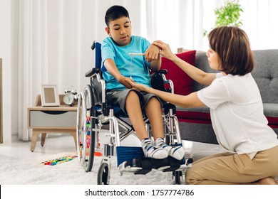 Portrait of asian physiotherapist carer helping and playing with special disabled child health problem by doing exercises sitting in wheelchair in rehabilitation clinic.disability care concept - Powered by Shutterstock