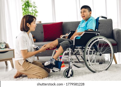 Portrait of asian physiotherapist carer helping and playing with special disabled child health problem by doing exercises sitting in wheelchair in rehabilitation clinic.disability care concept