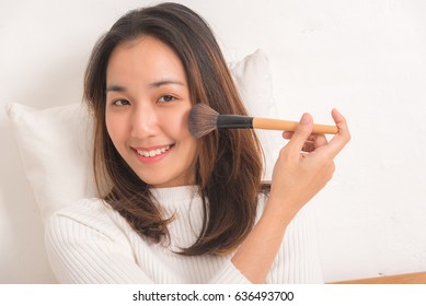 Portrait Asian Pretty Young Girl Smiling On Bed In Modern White Room In The Morning. She Looks Satisfied.make Up