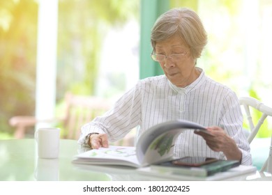 Portrait Of Asian Senior Elderly Woman Reading Books In Living Room 