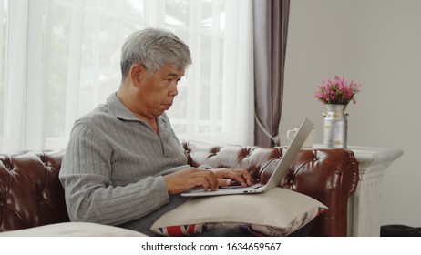 Portrait Asian Senior Man Sitting On Sofa In Living Room And Typing On Laptop Computer, Copy Space, , Senior Lifestyle Concept