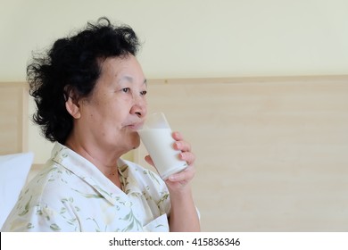 Portrait Of Asian Senior Woman Holding Glass Milk On Bed