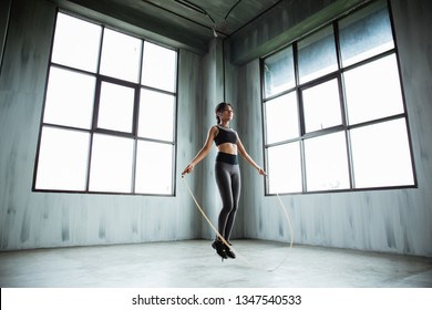 Portrait Of Asian Sport Young Woman Jumping Rope In The Gym