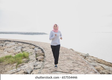 Portrait Of Asian Sporty Woman Wearing Hijab Jogging At The Jogging Track