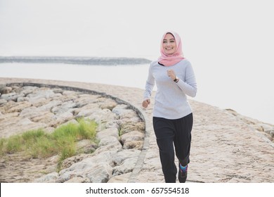 Portrait Of Asian Sporty Woman Wearing Hijab Jogging At The Jogging Track