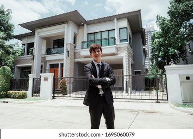 Portrait Of Asian Successful Businessman With A Big House At Background. Rich Guy With Gigantic House.