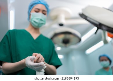 Portrait Of Asian Surgeon With Medical Mask Standing And Wearing Medical Gloves In Operation Theater At A Hospital. Team Of Professional Surgeons. Healthcare, Emergency Medical Service Concept