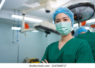 Portrait Of Asian Surgeon And Nurse With Medical Mask Standing With Arms Crossed In Operation Theater At A Hospital. Team Of Professional Surgeons. Healthcare, Emergency Medical Service Concept