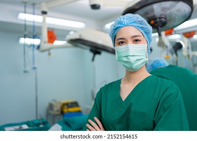 Portrait Of Asian Surgeon And Nurse With Medical Mask Standing With Arms Crossed In Operation Theater At A Hospital. Team Of Professional Surgeons. Healthcare, Emergency Medical Service Concept