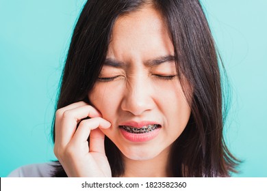 Portrait der asiatischen 10 schönen jungen Frau lächeln Zahnspangen auf den Zähnen lachen sie unglückliche Schmerzen Zahnschmerzen und Berührung Wange von Hand, einzeln auf blauem Hintergrund, Medizin und Zahnmedizin Konzept