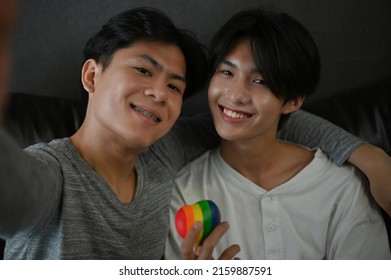 Portrait Of An Asian Teen Gay Couple Holding A Rainbow Heart. LGBT Pride Love Symbol. Homosexual Concept.