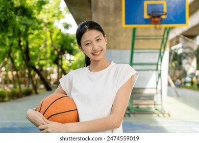 Portrait of asian teenager girl basketball player holding a basketball ball looking at the camera standing on the basketball court outdoors. Concept of sport, active lifestyle. Sports and recreation - Powered by Shutterstock