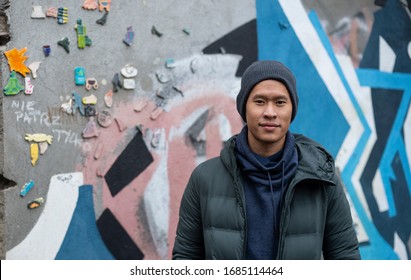 A portrait of an Asian Thai man wearing a winter jacket and a beanie hat in Krakow Poland