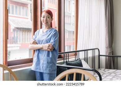 Portrait Of Asian Therapist Woman Nurse Wearing Medical Scrubs In The House Of Patient. Caregiver Visit At Home. Home Health Care And Nursing Home Concept.