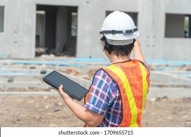 Portrait of Asian woman construction engineer worker with helmet on head using tablet while standing on construction site. building site place on background. Construction concept