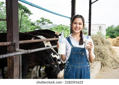 Portrait Of Asian Woman Dairy Farmer Holding Bottle Of Milk In Cowshed. Young Beautiful Female Agricultural Farmer Smile And Look At Camera After Milking Cow With Happiness At Livestock Farm Industry.