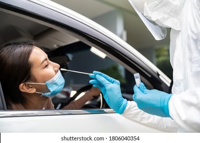 Portrait of asian woman drive thru coronavirus covid-19 test by medical staff with PPE suit by nose swab. New normal healthcare drive thru service and medical concept.