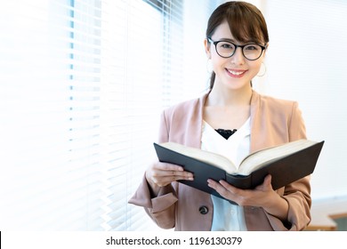 Porträt einer asiatischen Frau, die ein Buch hält.