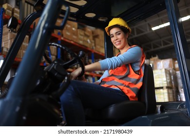 Portrait of asian woman industrial driver in work jacket sitting at steering wheel of forklift truck while working at factory warehouse. Factory worker female control forklift. - Powered by Shutterstock