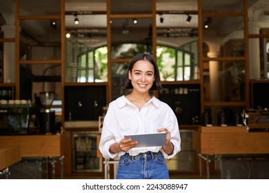 Portrait of asian woman, manager standing with tablet in front of cafe entrance, welcomes guests. Business and entrepreneurs concept - Shutterstock ID 2243088947