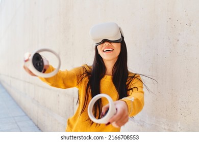 Portrait Of Asian Woman Playing In Metaverse Using VR Set Outdoors In The City