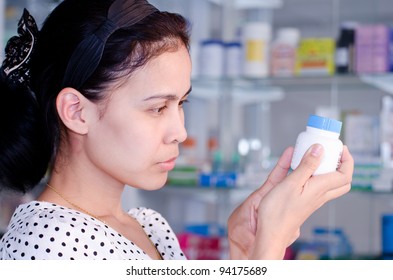 Portrait Of Asian Woman Reading Label Of Medicine In Drugstore.