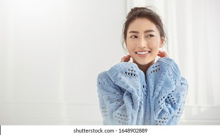 Portrait Of Asian Woman Relax Face In Winter Bedroom. Closeup Sexy Beauty Fashion Girl Healthy Makeup Facial Treatment Perfect Glow Skin. Smile Happy Asia Korean Girl Feel Cold In Sweater Hygge Style