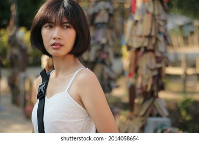 Portrait Of An Asian Woman With Short Hair, Not Looking At The Camera, In The Background. Attractions 