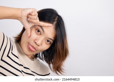 Portrait Of An Asian Woman Showing A Loser Symbol With A Funny Tongue Sticking Out.