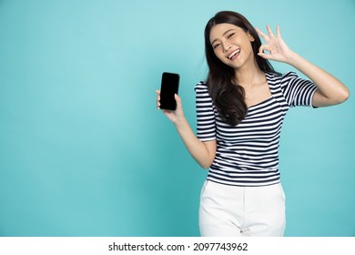 Portrait of Asian woman showing or presenting mobile phone application and ok sign isolated over green background, Asian Thai model - Powered by Shutterstock