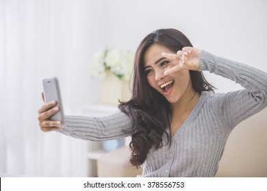 portrait of asian woman take photo of her self using smart phone camera