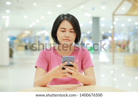 Portrait of Asian woman using smartphone on table at department store.