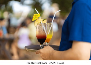 Portrait of Asian woman waiter serving food and drink to customer on the table at tropical beach cafe and restaurant on summer holiday vacation. Food and drink business service occupation concept.