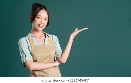 portrait of Asian woman wearing apron on green background - Powered by Shutterstock