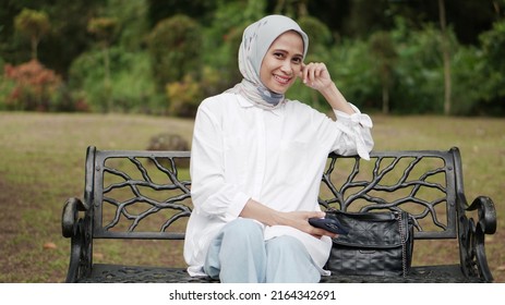 Portrait Of Asian Woman Wearing Hijab Sitting On Bench In The Park