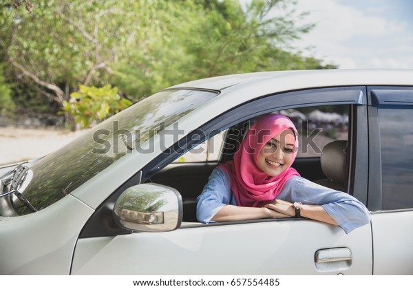 portrait of asian woman wearing hijab traveling\
with a car on summer\
holiday