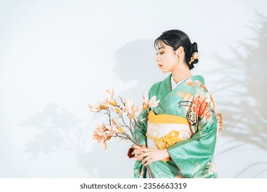 Portrait of an Asian woman wearing kimono with flowers. Japanese traditional dress. Pre-photoshoot at a photo studio for graduation ceremonies or coming-of-age ceremonies. Oriental beautiful woman.