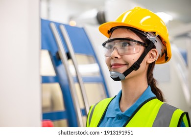 Portrait of Asian worker woman or engineer in safety helmet operating high technology factory machine at industrial plant. Industry people working on machinery. copy space