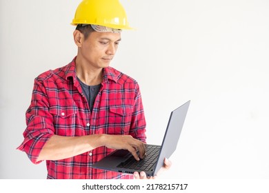 Portrait Of An Asian Working Man, Age 45+, Senior Engineer Concept. He Was Wearing A Red Plaid Shirt. Wear A Yellow Safety Helmet Standing In His Left Hand Holding A Black Laptop In White Background.