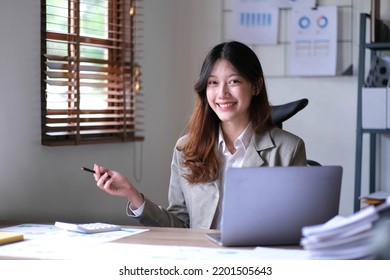 Portrait Of An Asian Young Business Female Working On A Laptop Computer In Her Workstation.Business People Employee Freelance Online Report Marketing E-commerce Telemarketing Concept.