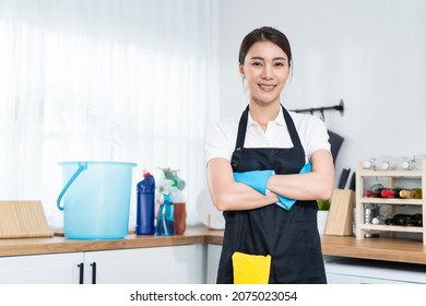 Portrait of Asian young cleaning service woman worker working in house. Beautiful girl housewife housekeeper cleaner crossing arm and smile, looking at camera after doing housework or chores at home. - Shutterstock ID 2075023054
