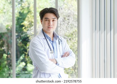 Portrait Of Asian Young Doctor Standing, Cross Arms Posing Near Windows In Medical Office. Ratio 16:9