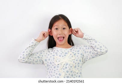 Portrait Of Asian Young Girl Grab Her Ears And Make A Cheeky Face On White Background.